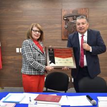 Rectora recibe placa de manos del director de GRANA