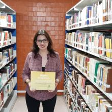 Profesora Maru Ruelas posando con su reconocimiento.