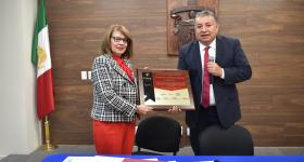 Rectora recibe placa de manos del director de GRANA